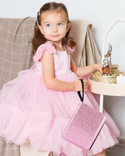 Klein meisje in roze jurk met roze tas